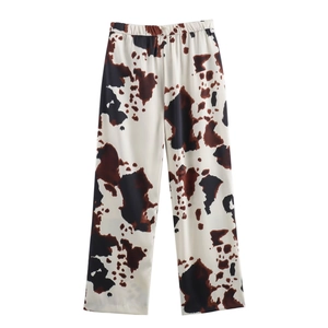Detailed flat lay of cow print trousers with elastic waist and brown spots on white