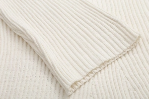 Detailed close-up of cream white ribbed knit fabric texture and cuff craftsmanship