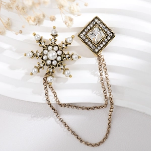 Detail of vintage gold snowflake brooch with pearls, rhinestones and double chains