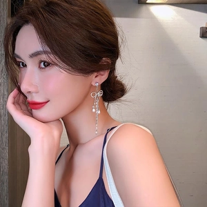 Elegant bow knot silver tassel earrings with pearls and rhinestones on female model