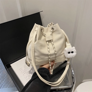 Cream white bucket bag with chain drawstring closure and plush monster keychain charm
