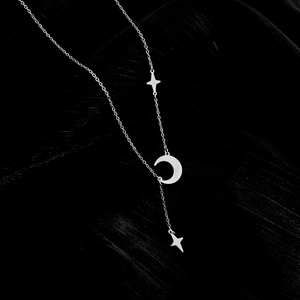 Close-up of a silver titanium steel Y-necklace with crescent moon and star pendants