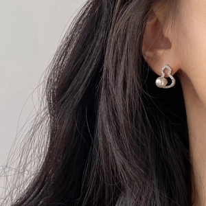 Elegant silver heart earrings with sparkling crystals and hanging pearl on a female model