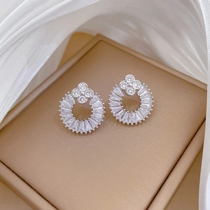 Detail of silver clover earrings with inlaid crystals on champagne silk texture