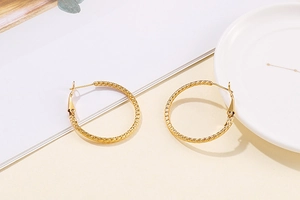Macro shot of gold stainless steel hoop earrings with textured spiral surface details