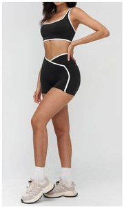 Detail of high-waist sports shorts featuring contrast piping and a V-shaped crossover waistband