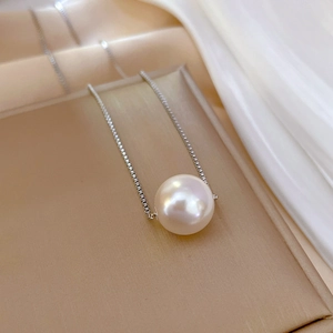 Macro detail of a high-luster pearl pendant on a sleek silver titanium steel chain