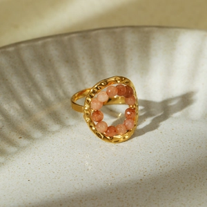 Detailed shot of hammered gold ring featuring a central oval bezel set with pink-orange beads