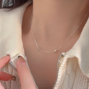 Close-up of a 925 sterling silver pearl necklace worn over a white knitted sweater