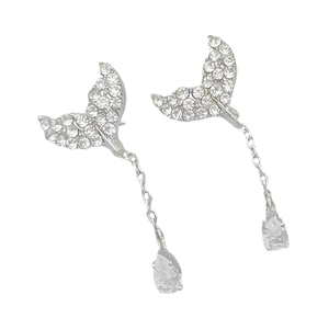 Close-up of silver mermaid tail earrings with shimmering pavé stones and pear-cut gems