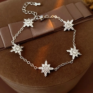 Détail d'un bracelet argenté avec pendentifs étoiles et zircons sur écrin en velours brun