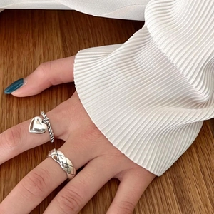 Detailed view of silver heart ring and quilted texture band worn on a hand