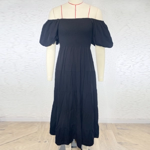 Detail of off-shoulder black tiered maxi dress with puff sleeves on display stand