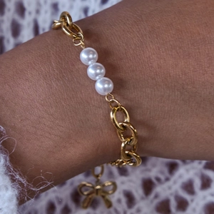 Détail d'un bracelet en acier inoxydable doré 18K avec nœud et perles sur le poignet