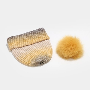 Détail du bonnet en maille dégradée avec pompon en fausse fourrure amovible et bouton pression