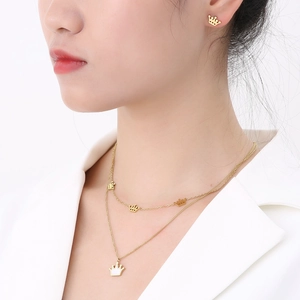 Close-up of a gold crown pendant necklace and earrings set worn by a female model