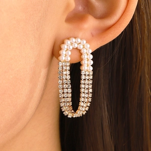 Elegant gold pearl heart drop earrings with tassels and rhinestones worn by a model