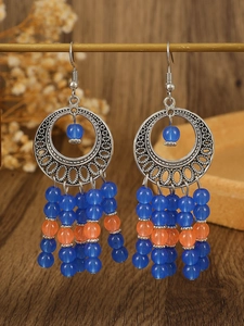 Detail of Bohemian hollow metal earrings with colorful seed bead tassels and ethnic patterns