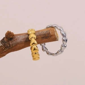 Artistic detail of gold and silver heart-shaped linked rings on a wooden branch
