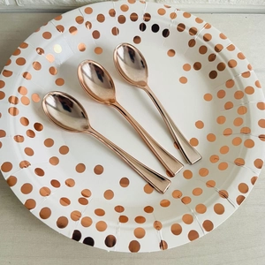 Detailed close-up of premium rose gold disposable plastic dessert spoons on a paper plate