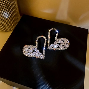 Macro shot of large heart-shaped silver earrings with sparkling crystals in a jewelry box