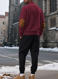 Detail of burgundy diamond-knit hoodie with elbow patches on a street background