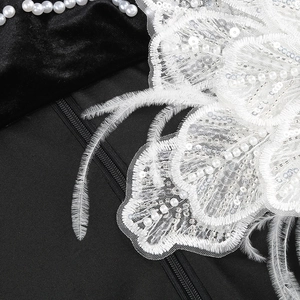 Détail de fleur en dentelle blanche, perles et paillettes sur une robe de soirée noire