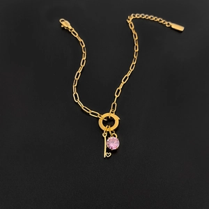 Detailweergave van titaniumstalen gouden armband met roze edelsteen en hartsleutel