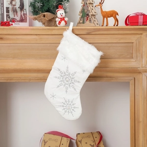 Detailed view of white plush Christmas stocking with silver snowflake and pearls on fireplace