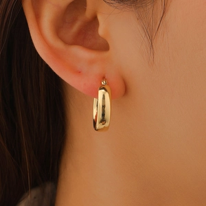 Minimalist gold-plated hoop earrings with a polished finish worn on earlobe