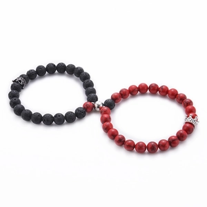 Detail of magnetic couple bracelets with white and black natural stones and crown charms