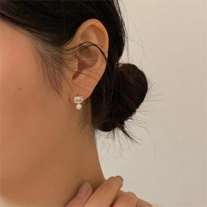 Detail of square zircon and pearl stud earring worn on model for a minimalist look