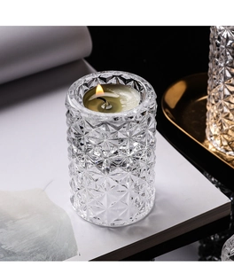 Detail of diamond-cut crystal glass candle holder with burning tealight on white surface