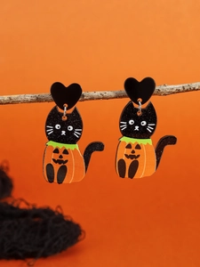 Close-up of Halloween black cat in pumpkin costume earrings hanging on a dry branch