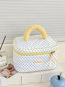 Close-up of quilted lemon dot toiletry bag with yellow handle and melody embroidery