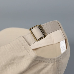 Detail of vintage copper metal buckle and cotton strap on a khaki baseball cap