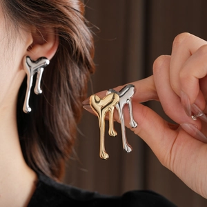 Macro shot of liquid metal heart tassel earrings in polished gold and silver finishes