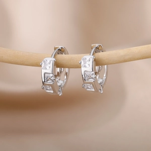 Close-up of silver-tone geometric C-shaped hoop earrings with square cubic zirconia stones