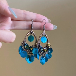 Detail of ethnic fish-shaped shell earrings with colorful beads and bronze fringe
