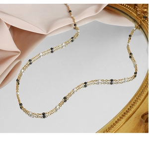 Detailed shot of double-layered gold necklace with black and white beads on mirror