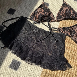 Détail du tissu en dentelle florale noire sur le haut de bikini et jupe de plage assortie