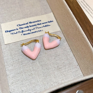 Minimalist pink and white heart-shaped hoop earrings in a wooden jewelry box