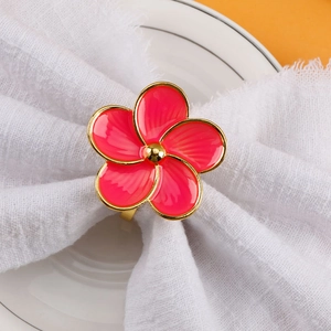 Pink five-petal flower napkin ring with gold edges on a white cloth for table decor