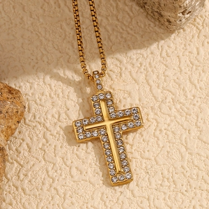 Macro shot of 18K gold plated cross necklace with inlaid crystals on stone texture