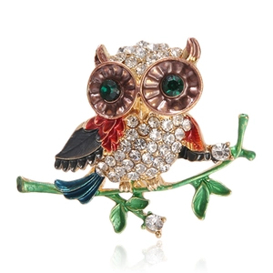 Close-up of golden owl brooch with colorful enamel and sparkling green rhinestone eyes