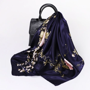 Detail of dark purple silk scarf with pink floral patterns draped over a black bag