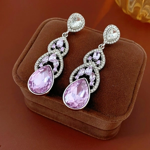 Détail des boucles d'oreilles argentées avec cristaux roses sur écrin en velours brun