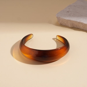 Artistic display of irregular amber resin open cuff bracelet with natural stone accents