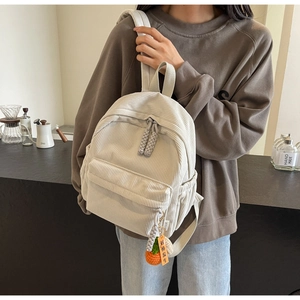 Detail of off-white corduroy mini backpack with woven zipper and khaki persimmon charm