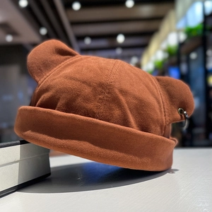 Close-up of brown knit cat ear beanie featuring decorative metal rings on the ears